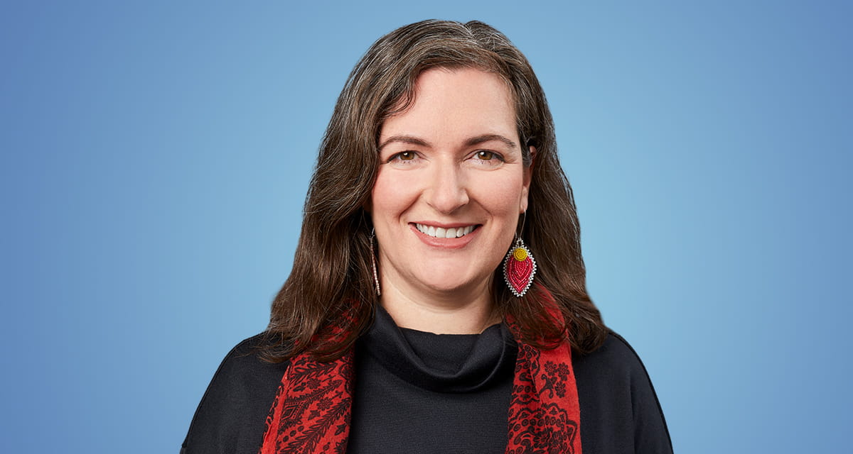 Photo portrait de Caitlin Burley portant un foulard rouge et une chemise noire.