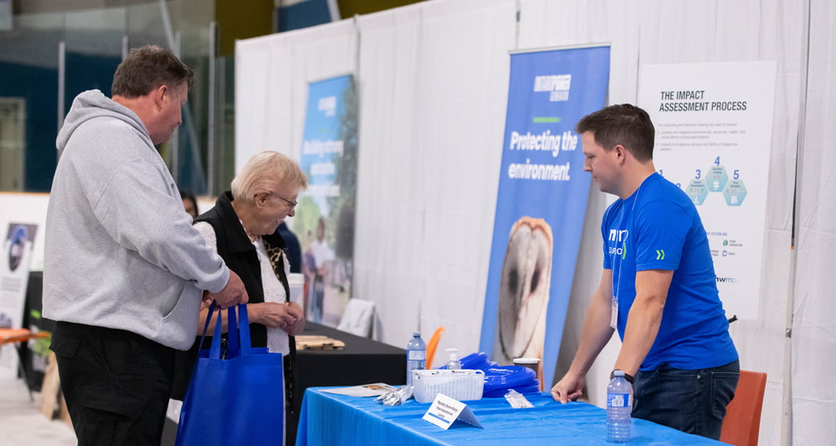 A photo showing an NWMO employee explaining the impact assessment process during an event.