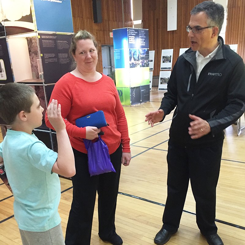 This photo shows a young boy and his mother speaking with NWMO's Senior Geologist Andre Vorauer during the open house.