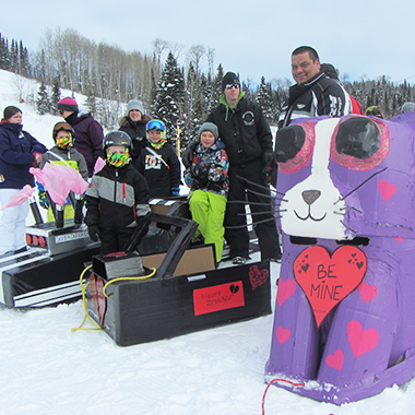 Ceci est une photo d’un groupe de familles de la localité avec leurs coureurs en boîte en carton au Kiwissa Ski Hill.