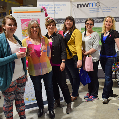 The photo shows six women, including a NWMO staff member, in front of the NWMO booth at the Ladies' Night in Blind River.