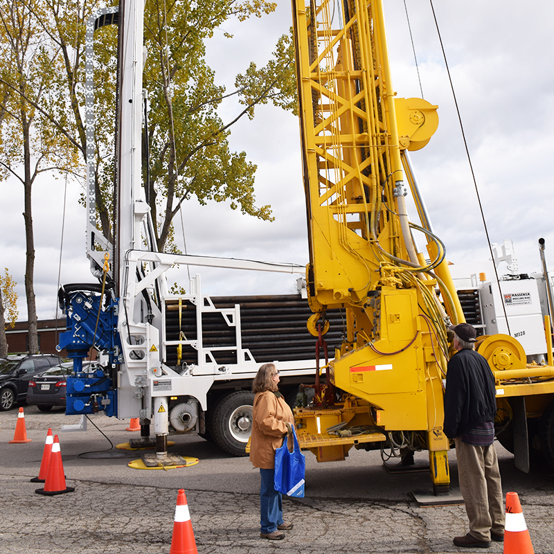 This photo depicts a South Bruce man and woman looking at a drill rig on display outside an open house held in Mildmay in early November.