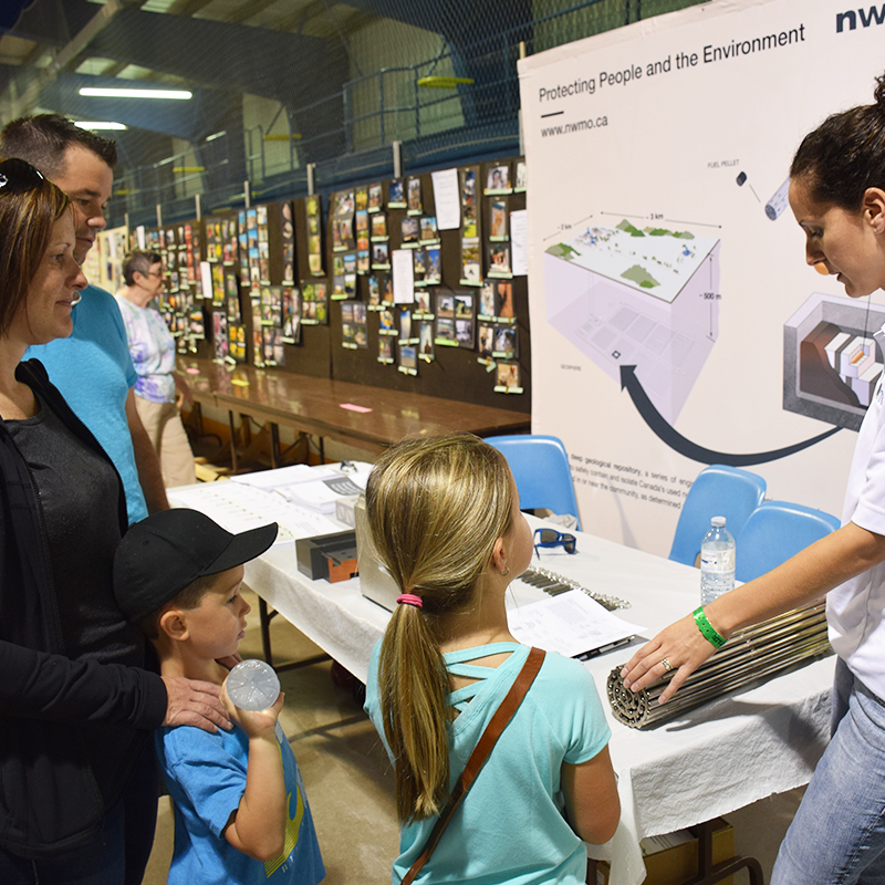 This photo depicts a family learning about used nuclear fuel from the NWMO’s Cherie Leslie at the Teeswater Fair.
