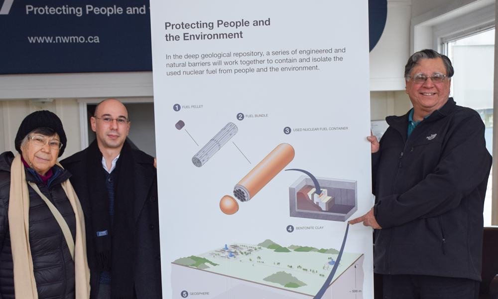 The photo shows a member of the Huron-Kinloss Community Nuclear Advisory Committee, posing in front of a rendering  of the used fuel repository, with his sister and nephew  at the Learn More Centre in Ripley. 