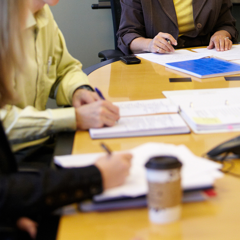 Generic image of documents on a table with people around it