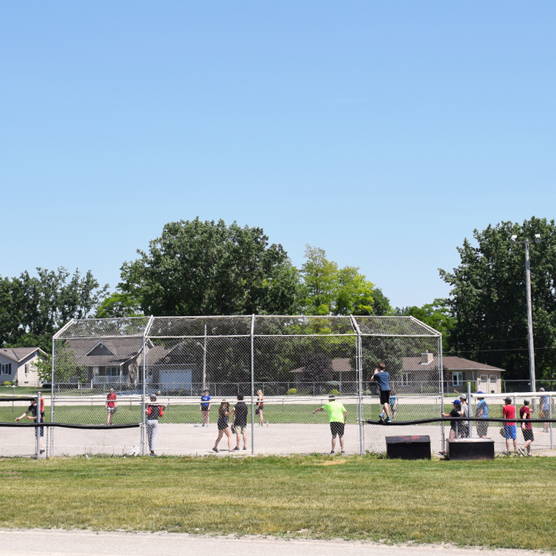 The photo shows a baseball diamond inside a large field, with children playing, and watching a ball game.