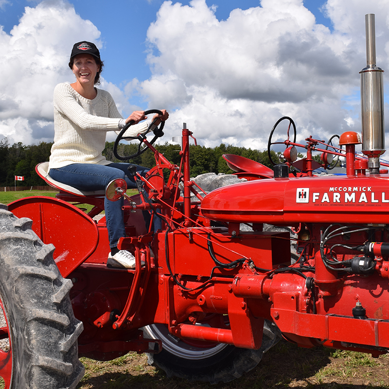 Cette photo illustre une employée de la SGDN assise dans un tracteur au Championnat international de labour à Walton