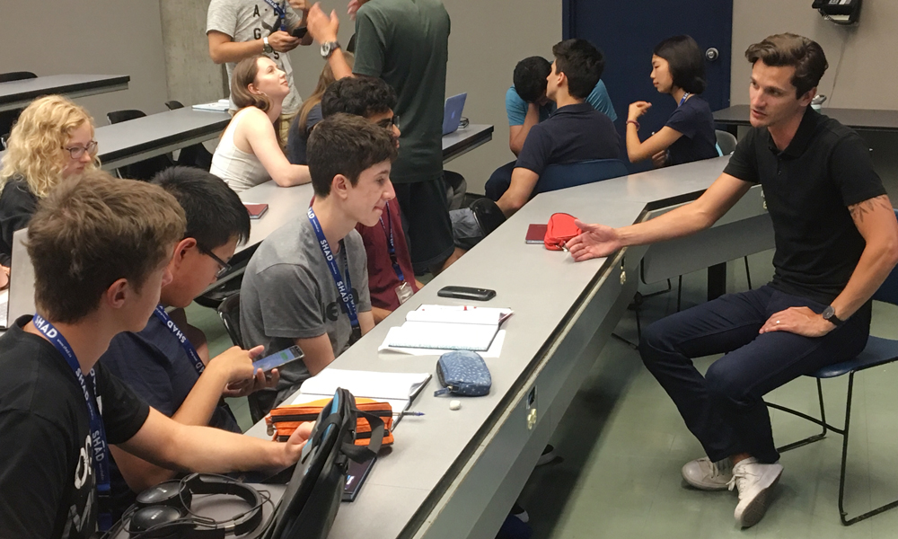 Image shows some students listening to a speaker in an informal classroom setting.