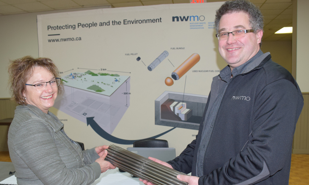 La photo illustre une femme tenant une maquette de grappe de combustible au kiosque de la SGDN au Complexe récréatif de Mildmay-Carrick