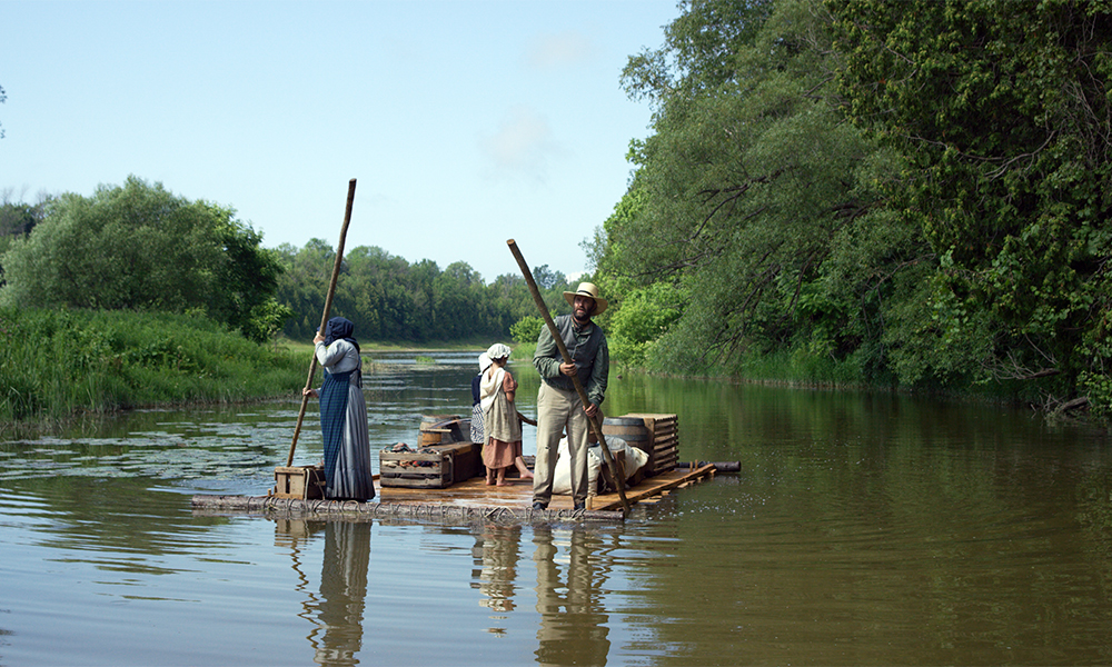 This photo shows a pioneer family in the early days of Bruce County poling down the river on a raft.