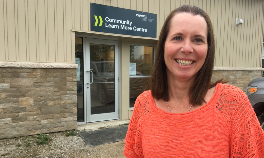 La photo montre une femme debout devant un bâtiment.