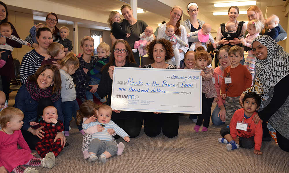 Colleen Shute, from Books in the Bruce, and Becky Smith, from the NWMO, get lots of help from the little ones for the presentation photo.