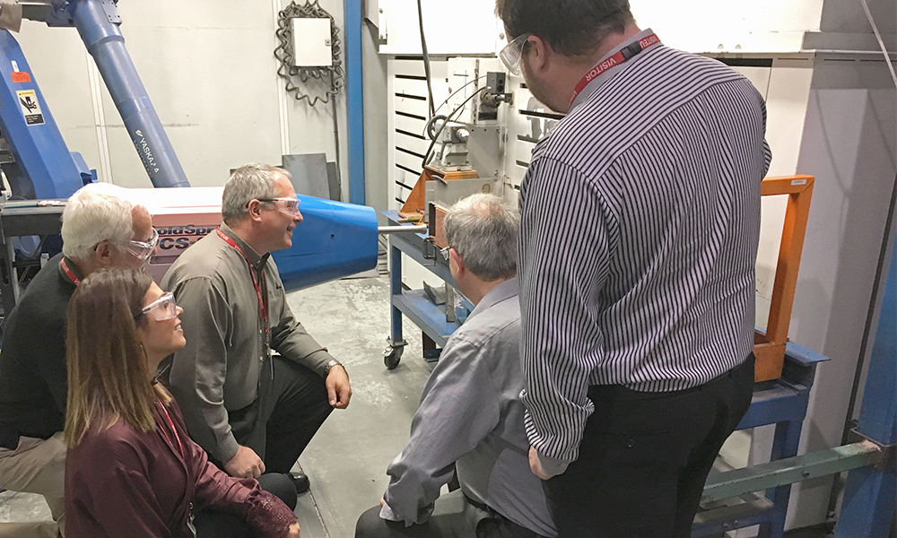 A group of people looks at machinery