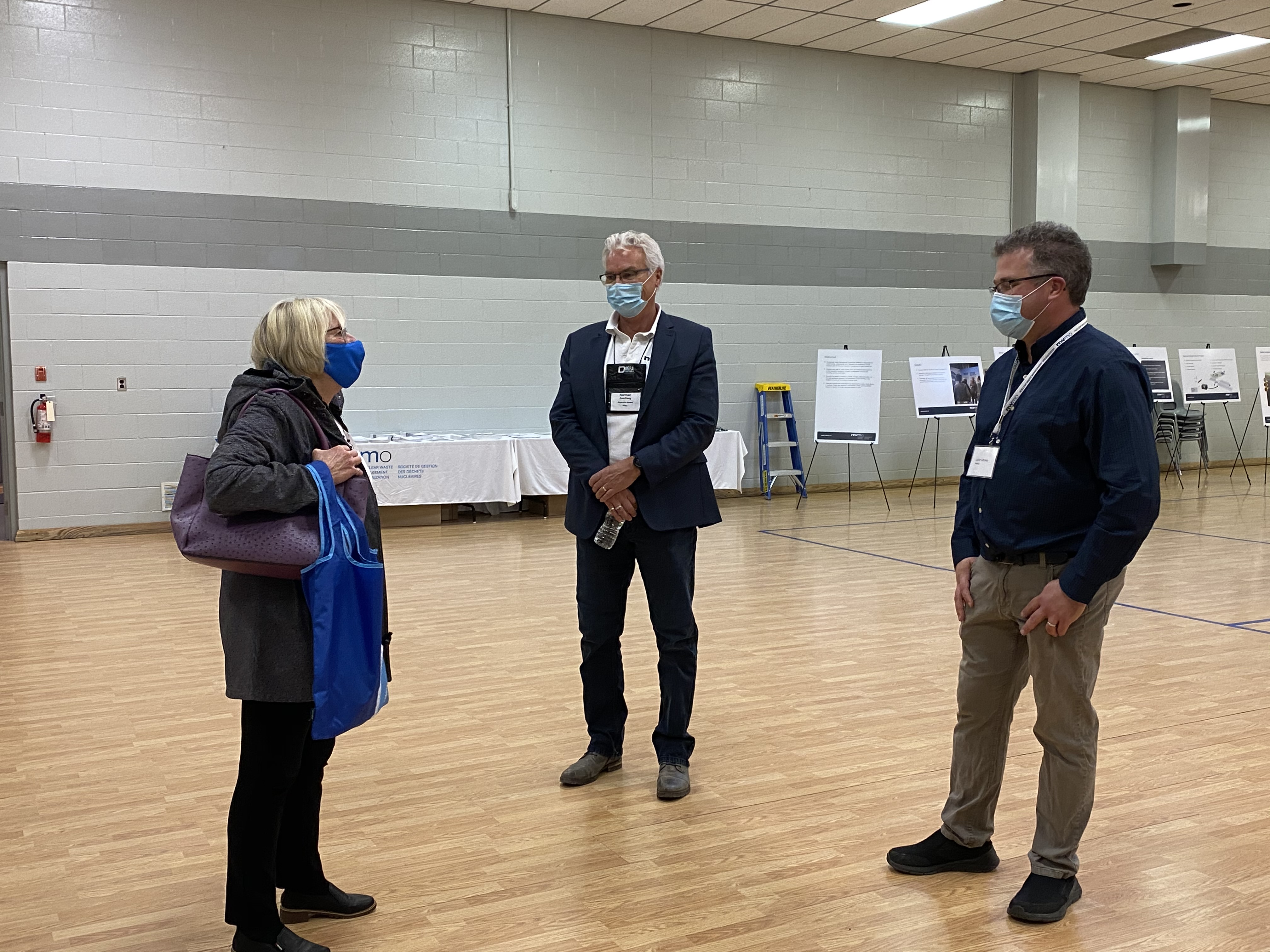 Three people socially distancing and wearing masks.