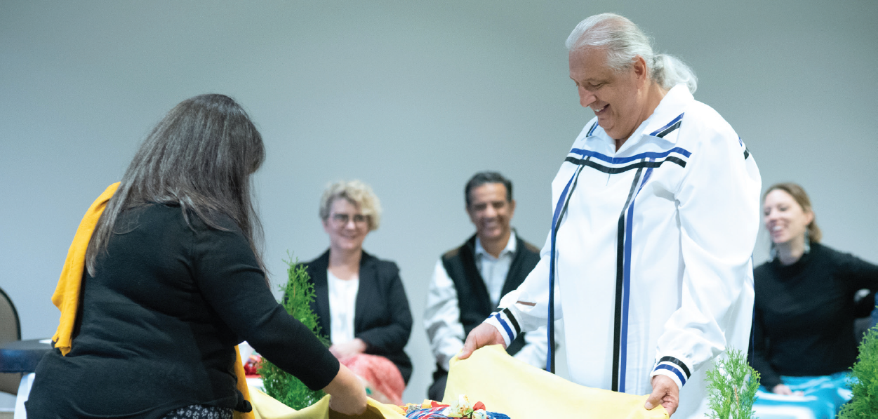 Jessica Perritt et Bob Watts, respectivement chef de la section du savoir autochtone et de la réconciliation et vice-président responsable des relations avec les Autochtones à la SGDN, rassemblent le ballot sacré lors de la cérémonie officialisant la Politique sur la réconciliation de la SGDN.