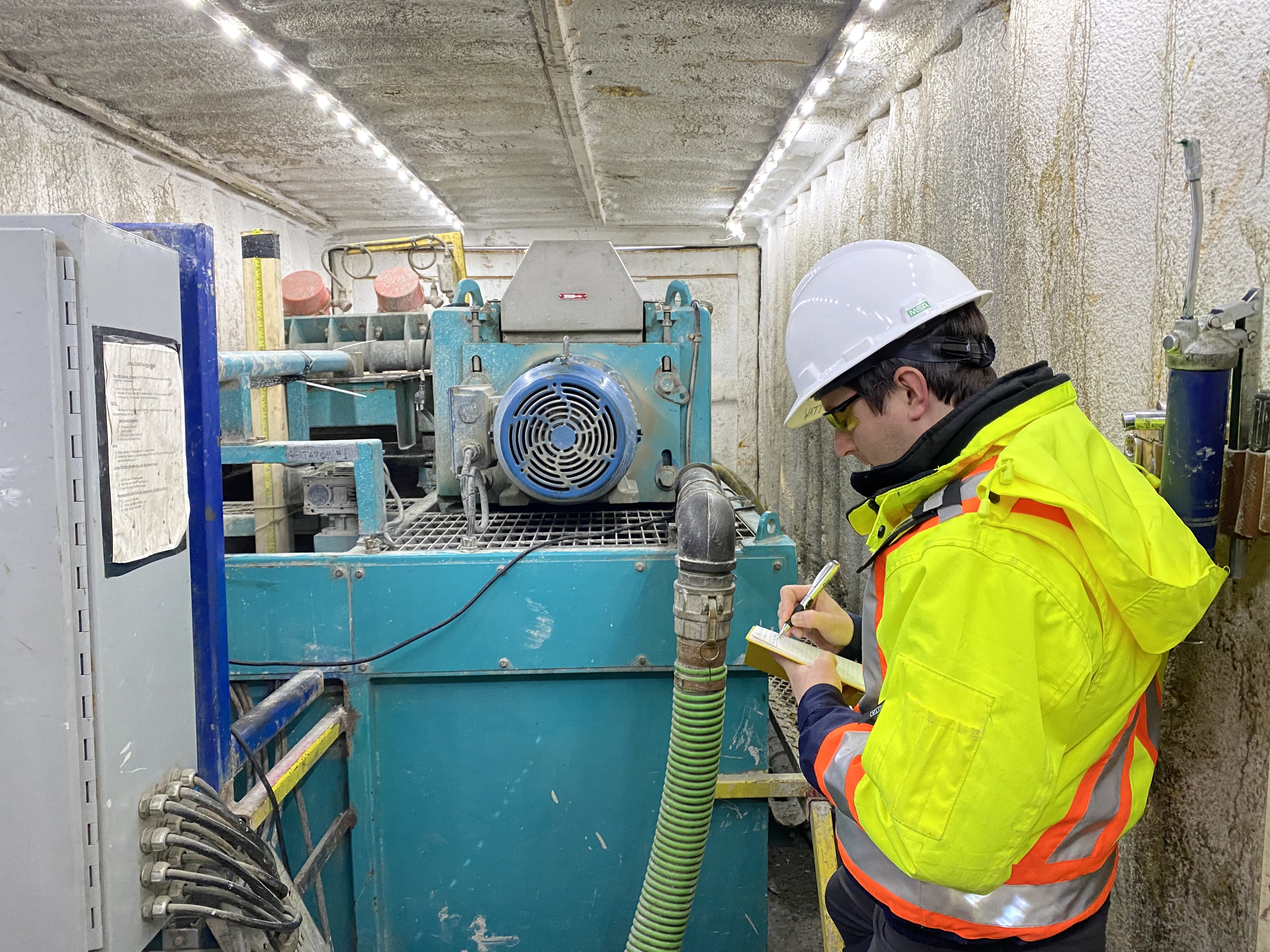 NWMO geologist inspecting the drill rig fluid recirculation system at a borehole site.