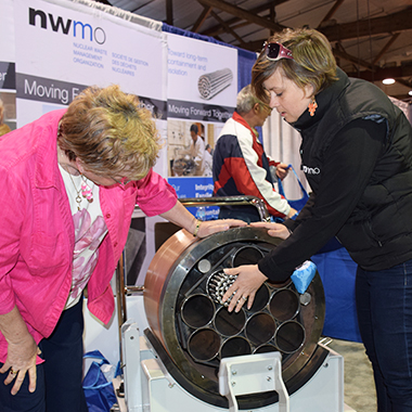 This photo shows an NWMO staff member showing a community member the model of the used nuclear fuel container.