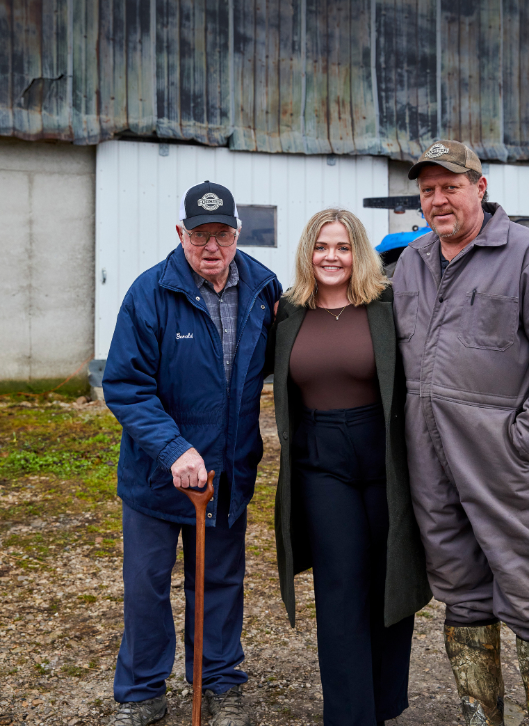 Three people standing in front of barn in South Bruce, Ontario.